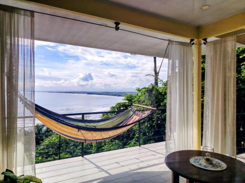 a hammock on a balcony with a view of the ocean at Mar y Sombra Villas in Quepos