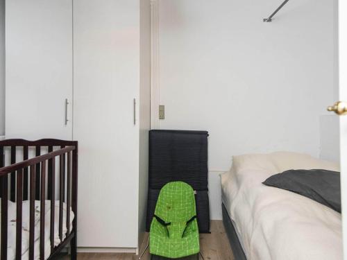 a bedroom with a crib and a green shoe next to a bed at 4 star holiday home in Hornsyld in Hornsyld