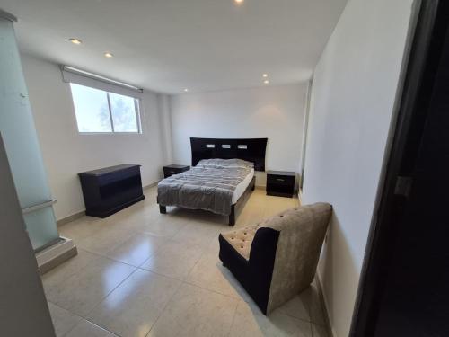 a bedroom with a bed and a couch and a window at Modern apartment Altravia 6 tower in Cholula