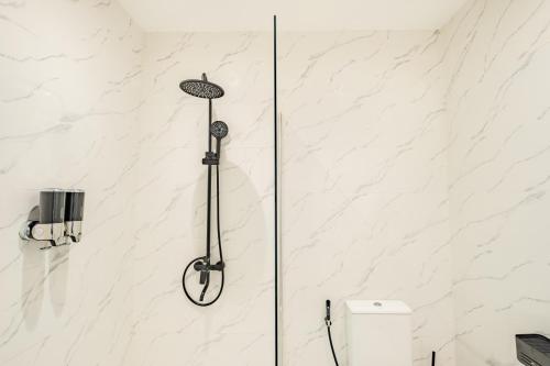 a shower in a bathroom with white marble walls at Avida Studios in Uluwatu - 5 mins walk to Thomas Beach in Uluwatu