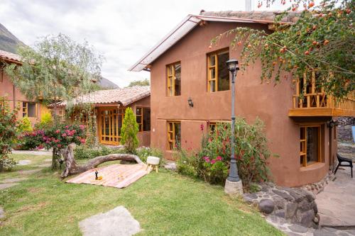 a house with a tree trunk in the yard at Unuwasi Hotel & Villa in Calca