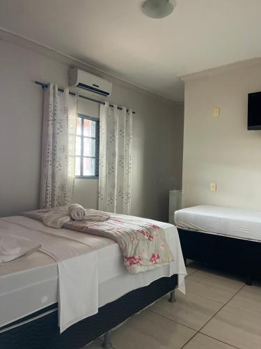 a bedroom with two beds and a window at Hospedagem Riazo in Pirenópolis