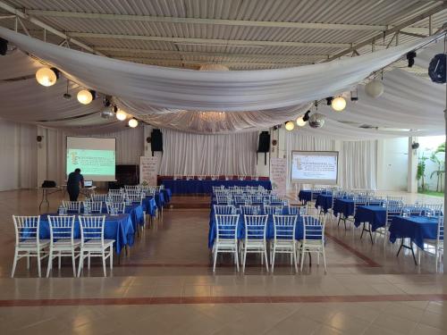 a room with blue chairs and a man giving a presentation at Hotel & Balneario Los Angeles in Taxco de Alarcón