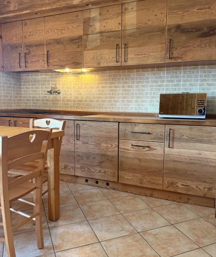 a kitchen with wooden cabinets and a table and a microwave at Case Vacanza Perron in Sauze dʼOulx