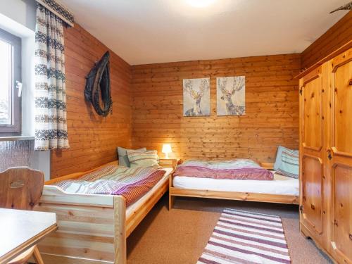 two beds in a room with wooden walls at Amberg in Schwoich