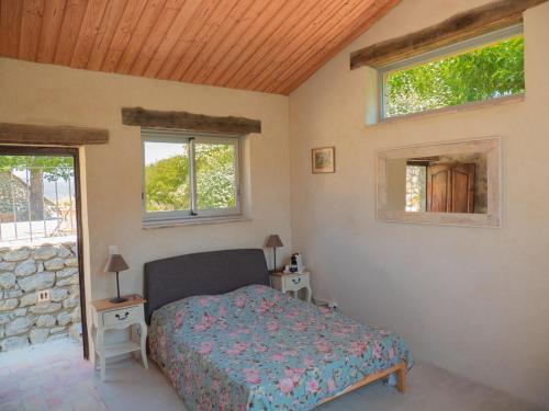 a bedroom with a bed and two windows at Le Serre des Granges Plus in Montaulieu