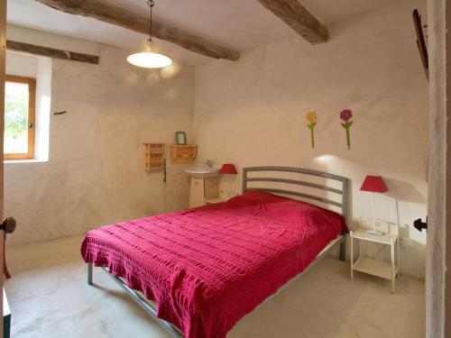 a bedroom with a bed with a red blanket at Le Serre des Granges in Montaulieu