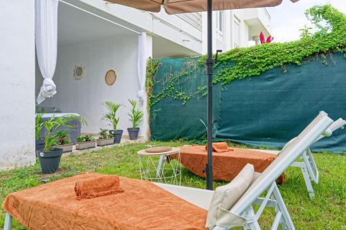 a patio with an umbrella and a table and chairs at Nid rose paradis secret au robert avec jacuzzi in Le Robert