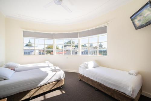 two beds in a room with two windows at Knickerbocker Hotel in Bathurst