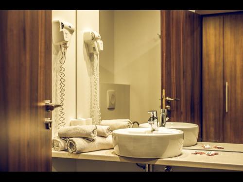a bathroom with a sink and a phone in a mirror at Hotel Oscar in Campina