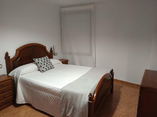 a bedroom with a bed with white sheets and a window at Casa Atalaya en Malpica in Malpica