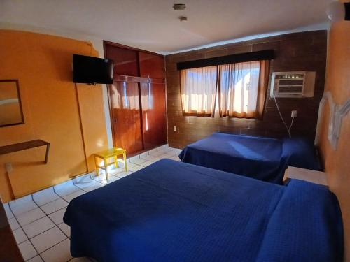 a hotel room with two beds and a television at Hotel Santa María in Mazatlán