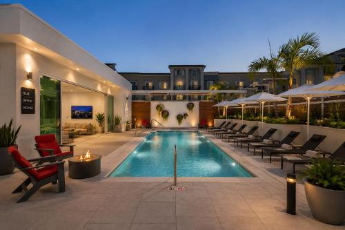 a swimming pool with lounge chairs and a building at Splendid Executive Suites in Long Beach