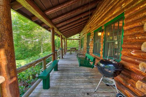a porch of a log cabin with benches and a grill at Winds Aloft in Newland