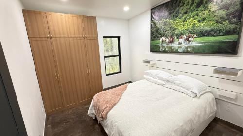 a bedroom with a bed and a painting on the wall at Glacier Luxury Retreat Oak Tree Apartment 3 in Hungry Horse