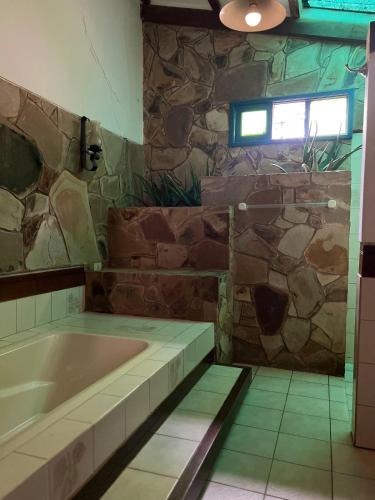 a bath tub in a bathroom with a stone wall at Casa Alquimia Completa in Samaipata