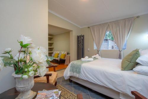 a bedroom with a bed and a vase with flowers on a table at Baobab at 36 Rissik in Komatipoort