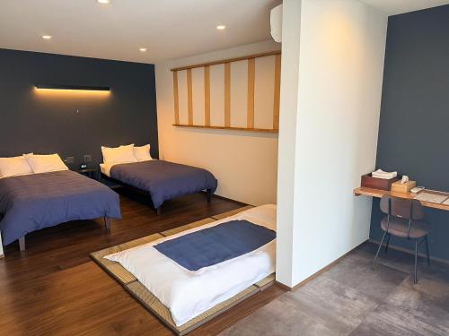 ein Zimmer mit zwei Betten und einem Tisch darin in der Unterkunft Zenya-Nakano in Nakano