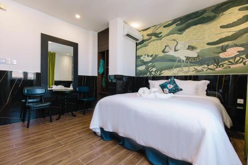 a bedroom with a large white bed with a painting on the wall at Orchid Hotel in Hue