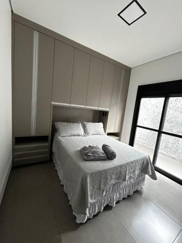 a bedroom with a bed and a large window at Maggi Residence in Batatais