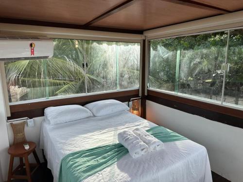 a bedroom with a bed and two large windows at Casa Monan Atins Beach in Barreirinhas