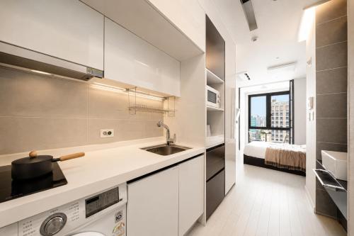 a white kitchen with a sink and a stove at Urbanstay Seomyeon in Busan