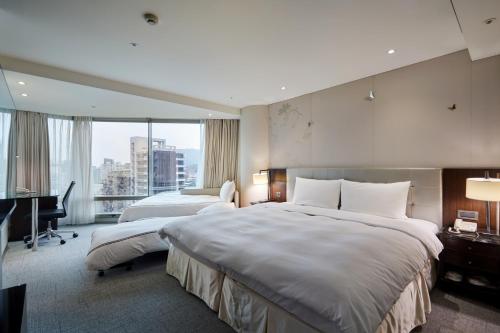 a hotel room with two beds and a desk at K Hotel Taipei Dunnan in Taipei