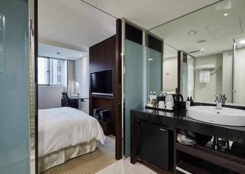 a bathroom with a bed and a sink and a mirror at K Hotel Taipei Dunnan in Taipei