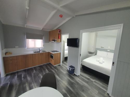 a room with a bedroom with a bed and a tv at Riverside Cabin Park in Shepparton