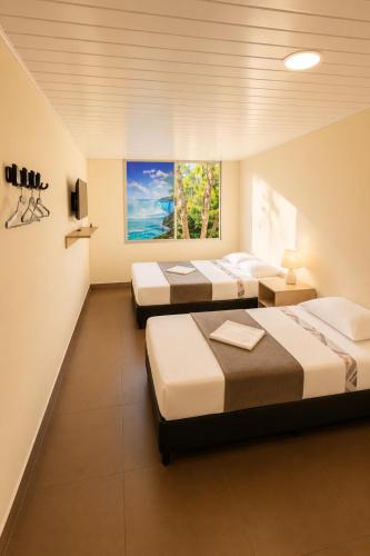 a row of four beds in a room at Hotel Arboleda de Cádiz in Ibagué