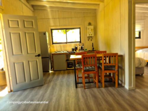 a small kitchen with a table and chairs and a door at cabañasmanantialpanguipulli in Panguipulli
