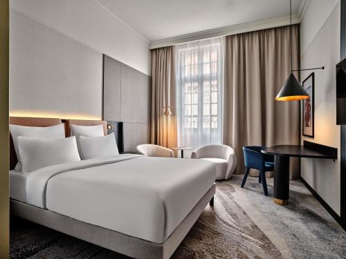 a hotel room with a large bed and a desk at Mövenpick Grand Hotel Wroclaw in Wrocław