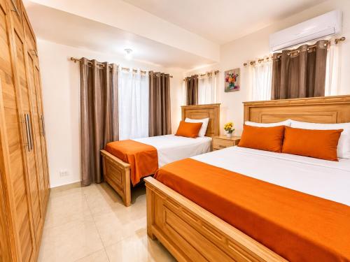 a bedroom with two beds with orange pillows at Modern Villa 2 BR Near Airport, Beaches, Dining in Punta Cana