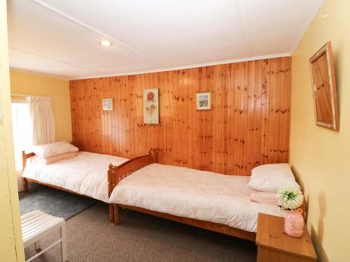 two beds in a room with wooden walls at Forest View in Teeranearagh