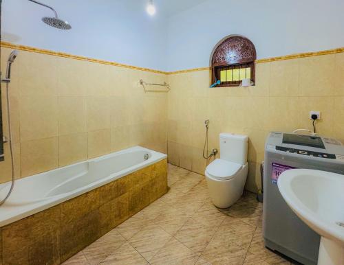 a bathroom with a tub and a toilet and a sink at Senu Bungalow in Ragama