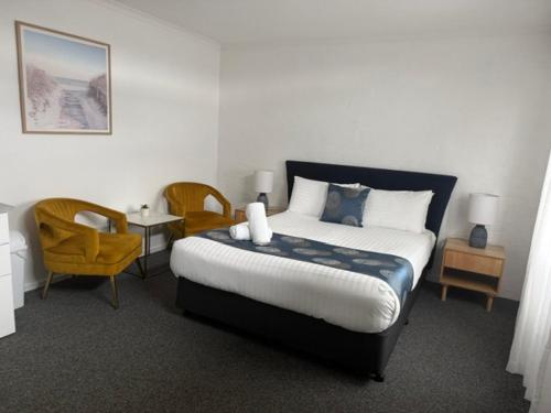 a bedroom with a bed and two chairs and a table at Caledonian Inn - The Stump in Port Fairy