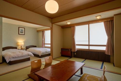 a bedroom with two beds and a table and chairs at Nishihoppo Onsen HOTEL in Yamanouchi