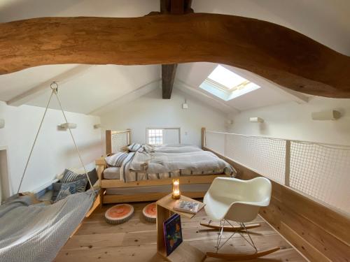 a attic bedroom with a bed and a white chair at 蔵Mping Hotel in Fukaya