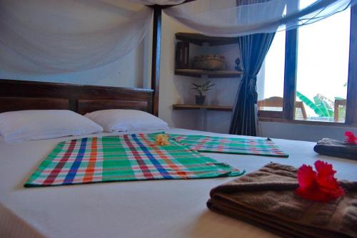 a bed with a colorful blanket and towels on it at Cili Hotel & Pizza Restaurant in Arugam Bay
