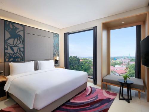 a bedroom with a large white bed and large windows at Mercure Berau in Tanjungredep