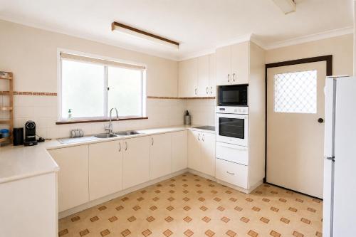 a kitchen with white cabinets and a window at Smugglers Cove in Esperance
