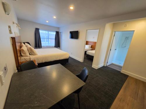 a hotel room with a bed and a table at Waikato Hospital Motel in Hamilton