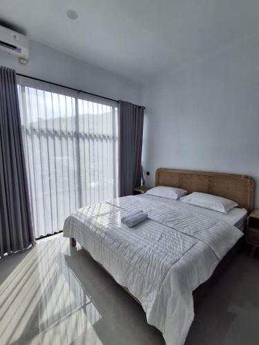 a bedroom with a large bed and a large window at Poshaka Karimunjawa in Karimunjawa
