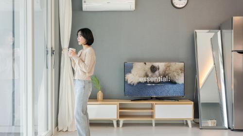 a woman standing in front of a tv holding a cup at Sara&Forest Pension Mungyeong in Mungyeong