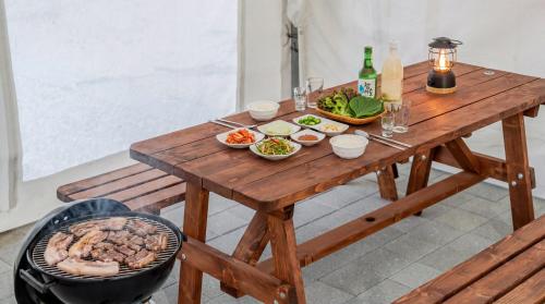 a wooden table with plates of food and bottles of wine at Sara&Forest Pension Mungyeong in Mungyeong