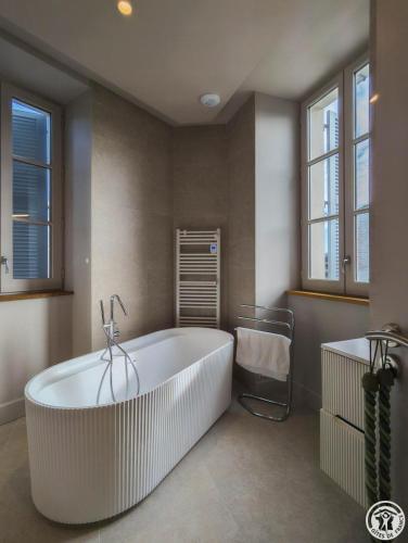 a large white tub in a bathroom with windows at La villa saviesa in Cazères