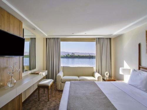 a hotel room with a bed and a large window at Mövenpick Royal Lotus Nile Cruise, Every Monday Four Nights From Luxor, Every Friday Three Nights From Aswan in Luxor