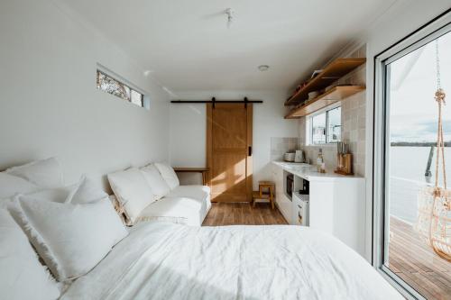 a bedroom with a white bed and a large window at The Floathouse - Floating tiny home on the Murray in White Sands