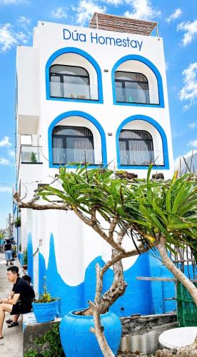 a blue and white building with a tree in front of it at Dứa Homestay in Cu Lao Thu