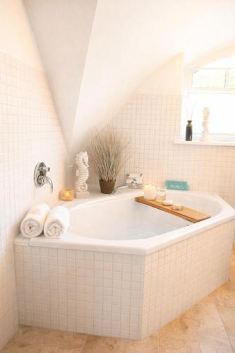 a white bath tub in a white tiled bathroom at Reethus-am-Hafen Reetdachhaus Hafenblick mit Garten und Blick aufs Wasser in Rankwitz